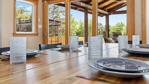A dining area with a wooden table set for six, surrounded by tall, textured glass candle holders. - Fun House with Pool, Hot Tub, Cool Outdoor Living Space (Centennial)