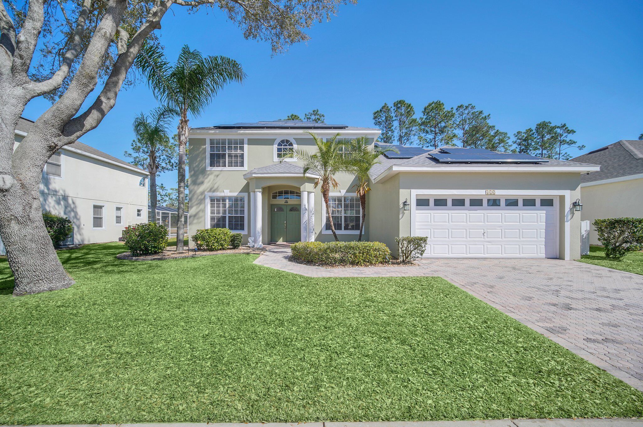 A two-story house with a garage, solar panels, and a well-maintained lawn.