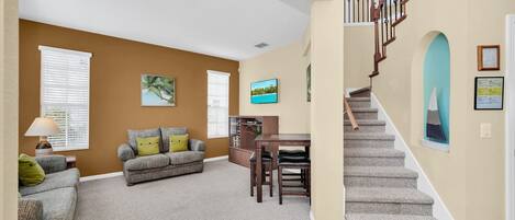 A living room with a sofa, a dining table, and a staircase.
