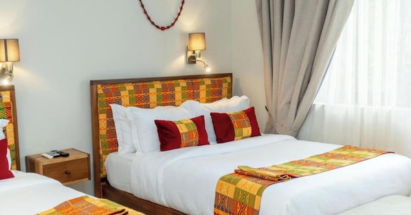 Habitación de hotel con una cama grande, dos mesitas de noche y un cabecero con un estampado colorido.
