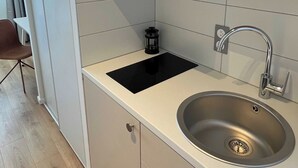 Een moderne keuken met een RVS spoelbak, een zwart inductiekookplaat en een inbouwoven.