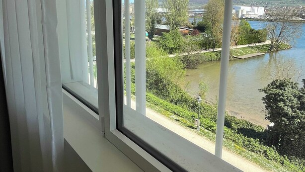 Een uitzicht op een rivier, groen en gebouwen in de verte.