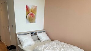 Een moderne slaapkamer met een bed, een aan de muur bevestigd beeld van perziken en een houten vloer.