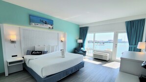 A hotel room with a large bed, a view of the sea, and a balcony with a railing. - The Chart House Marina Hotel (Clearwater Beach)