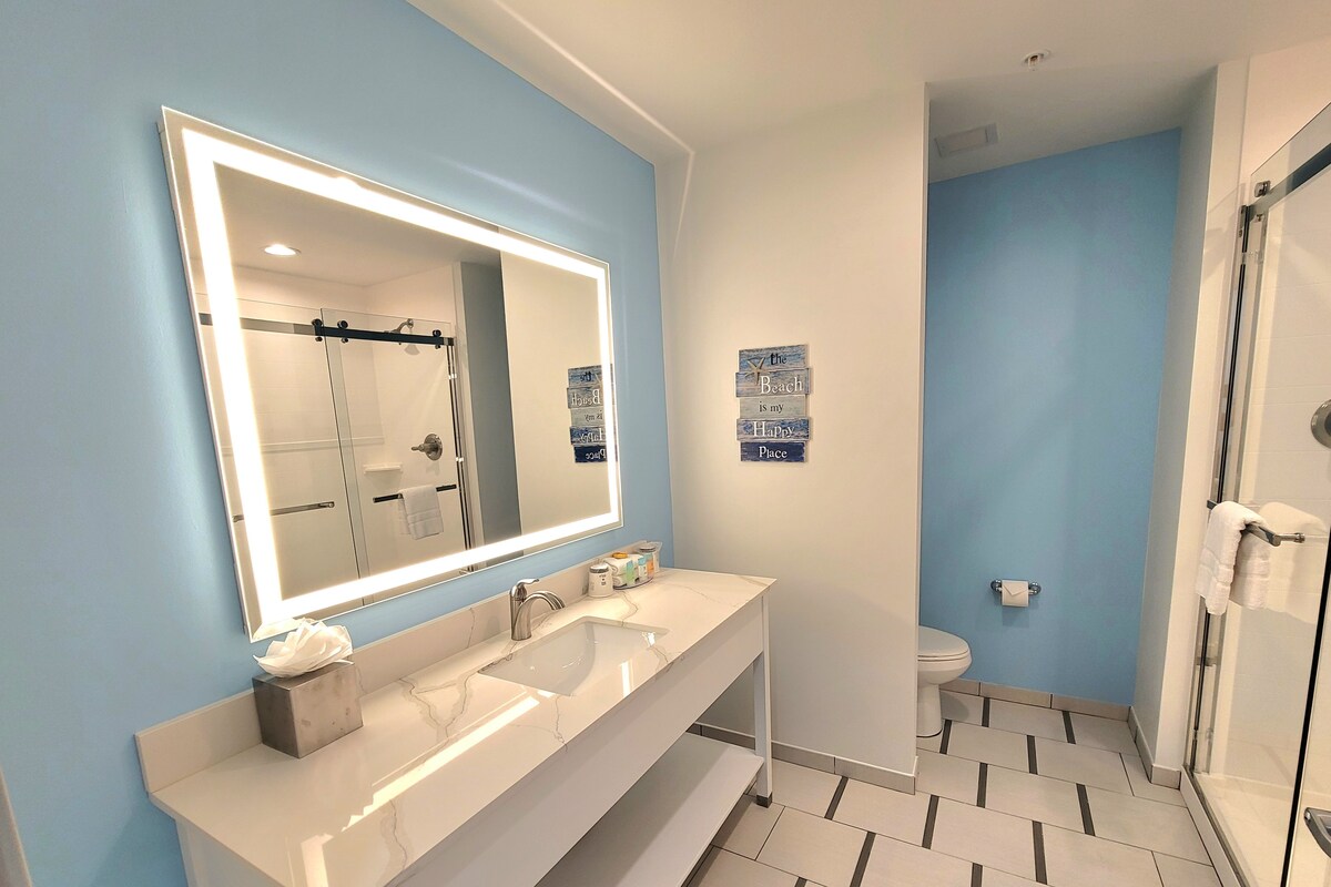 Une salle de bain moderne avec un grand miroir, deux lavabos, une douche et des toilettes.