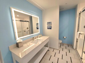 Une salle de bain moderne avec un grand miroir, deux lavabos, une douche et des toilettes.