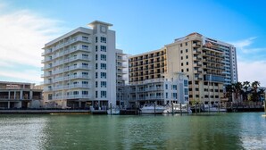 A waterfront hotel with multiple balconies, a marina with boats, and a clear sky. - The Chart House Marina Hotel (Clearwater Beach)