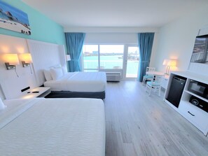 Une chambre d’hôtel avec deux lits, un coin repas et vue sur la mer.