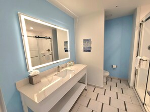 Un baño moderno con un espejo grande, dos lavamanos, una ducha y un inodoro.