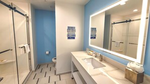 Une salle de bain moderne avec un grand miroir, une douche et des toilettes.