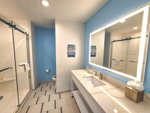 A modern bathroom with a large mirror, a shower, and a toilet. - The Chart House Marina Hotel (Clearwater Beach)