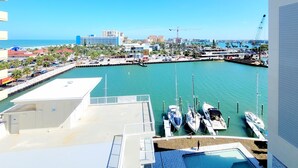 Un puerto deportivo con barcos amarrados, cielo azul despejado y edificios al fondo.
