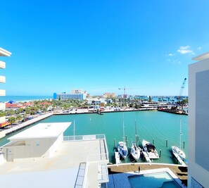 Un puerto deportivo con barcos amarrados, cielo azul despejado y edificios al fondo.