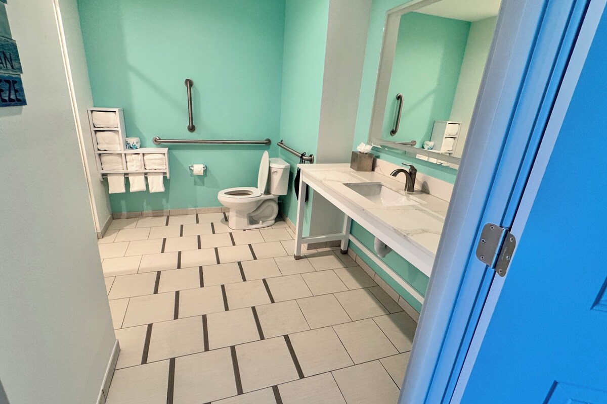 Une salle de bain équipée de toilettes, d’un lavabo et de barres d’appui.