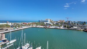 A marina with multiple yachts docked, a pier extending into the water, and a cityscape in the background. - The Chart House Marina Hotel (Clearwater Beach)