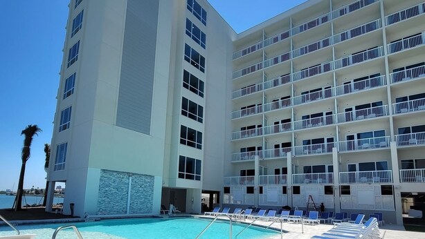 A hotel pool area with sun loungers and a clear blue pool. - The Chart House Marina Hotel (Clearwater Beach)