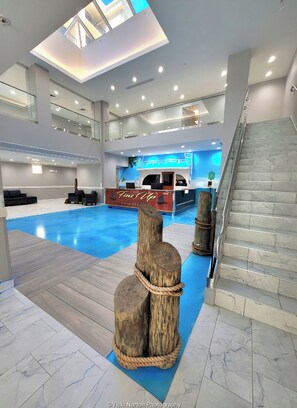 Un vestíbulo amplio con vistas despejadas a la recepción, un área de piscina y una escalera.