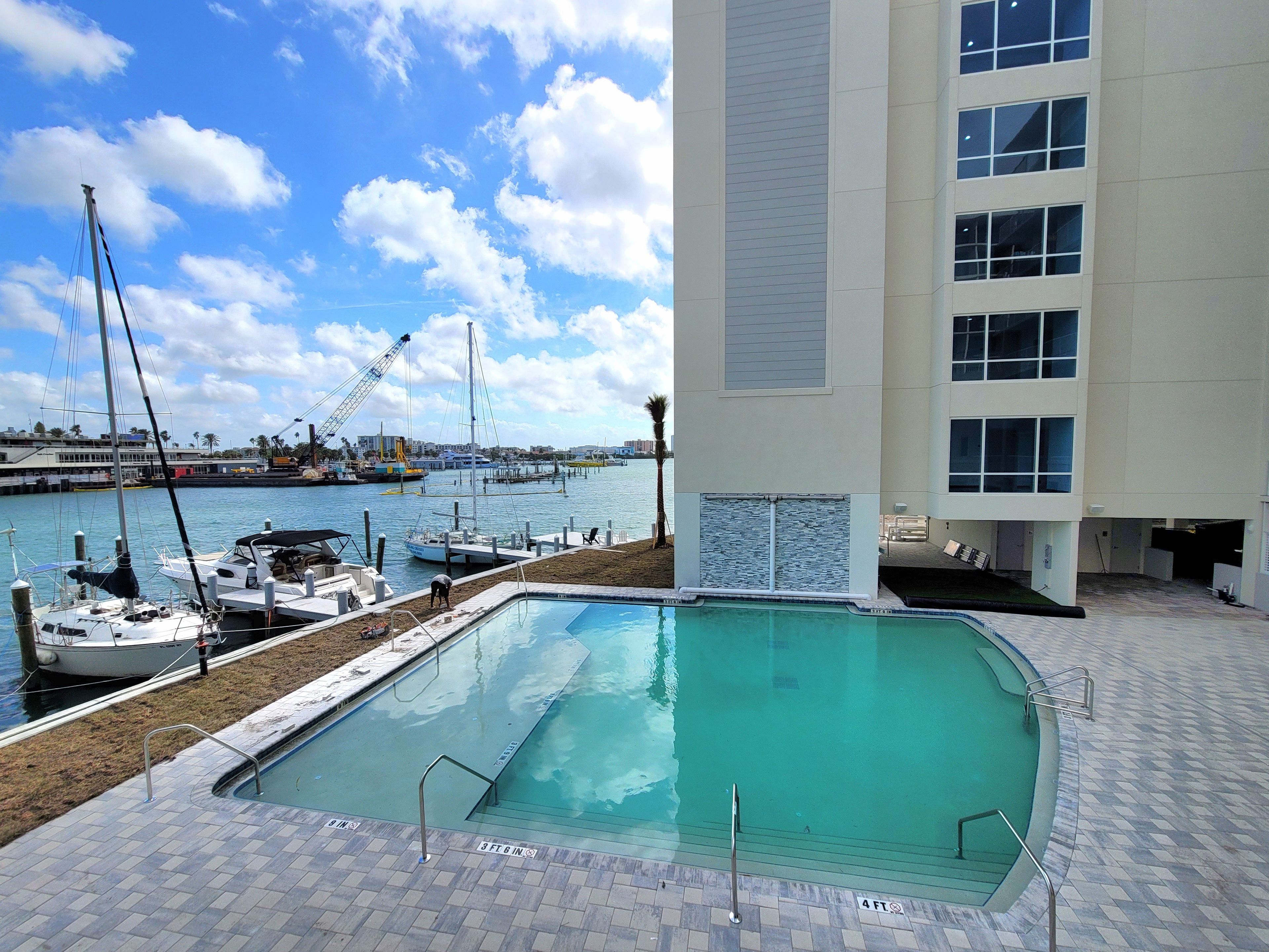 A swimming pool with a view of the marina and a building with multiple windows.