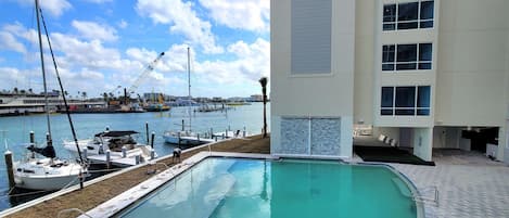A swimming pool with a view of the marina and a building with multiple windows.