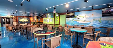 A restaurant with wicker furniture, a blue floor, and a mural of a boat on the wall.