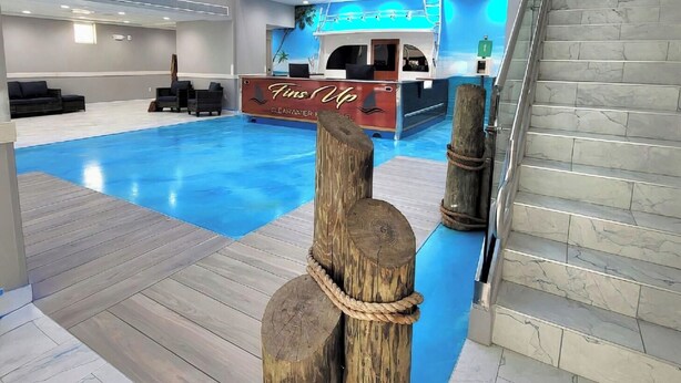 Un moderno vestíbulo de hotel con piscina, mostrador de recepción y una escalera.