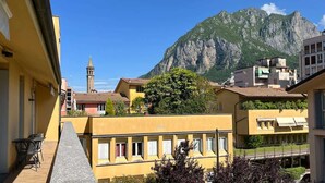 Un bâtiment jaune avec un balcon, une montagne en arrière-plan et une tour.