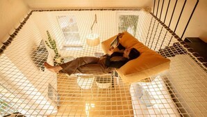 A person lying on a hammock in a room with a net ceiling, a window, and a plant. - Casa Iride - Affitti Brevi Italia (Lecco)