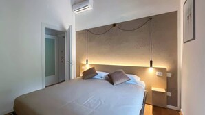 A bedroom with a bed, two bedside lamps, a door, and a wall-mounted air conditioner. - Casa Iride - Affitti Brevi Italia (Lecco)