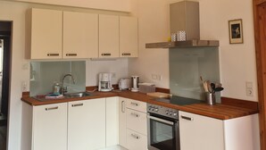 A modern kitchen with white cabinets, wooden countertops, a built-in oven, and a stainless steel range hood.