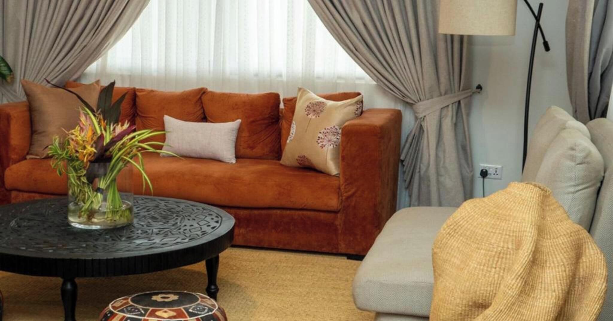 Een woonkamer met een bruine bank, een ronde salontafel en een bijzettafeltje.