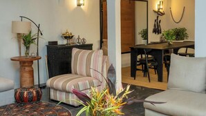 A living room with a striped armchair, a round wooden table, and a dining area with a wooden table and chairs.