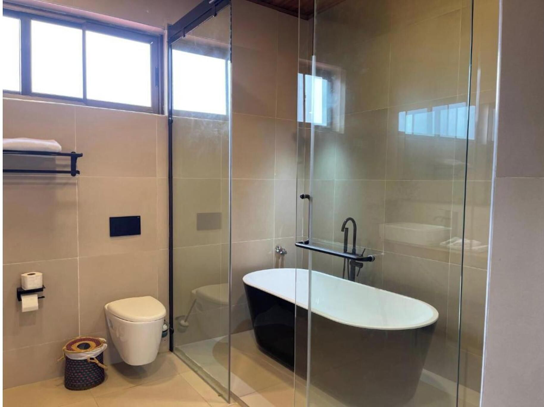 Un baño moderno con ducha de vidrio, una bañera independiente y un inodoro.