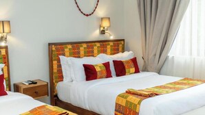 Ein Hotelzimmer mit einem großen Bett, zwei Nachttischen und einem Kopfteil mit farbigem Muster.