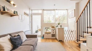 A modern living room with a sofa, a small kitchen area, and a staircase. - Urban loft with private garden - hyper center (REIMS)