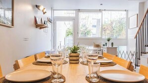 A dining area with a wooden table set for two, clear glassware, and a small plant centerpiece. - Urban loft with private garden - hyper center (REIMS)