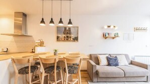 A modern kitchen with a dining table and chairs, a sofa, pendant lights, and a framed picture on the wall. - Urban loft with private garden - hyper center (REIMS)