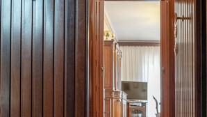 Un couloir aux murs lambrissés et un paillasson sur lequel on peut lire : « EN VACANCES chez les GRANDS-PARENTS ».