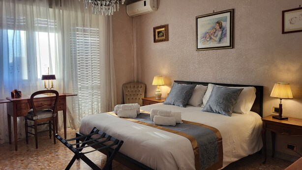 Une chambre d’hôtel avec un lit, un bureau, une chaise, une lampe et un tableau au mur.