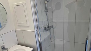 A modern bathroom with a glass shower enclosure, a white sink, and a mirror. - Comfort Appt in a Premium Residence- Sport/cinema (Huningue)