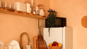 A compact kitchen with a sink, countertop, and shelves for dishes and utensils. - NEW apartment costa da Caparica - 350 meters from the beach - boho style T2 (Costa da Caparica)
