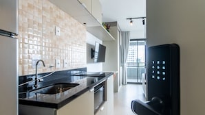 A modern kitchen with a built-in oven, a microwave, and a stainless steel sink. - Cozy Near Allianz Parque Sp-p1301b (São Paulo)