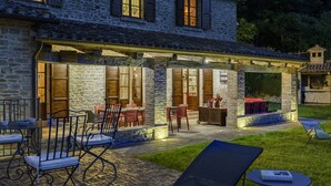 A stone building with a covered patio area featuring outdoor seating and a small pool.