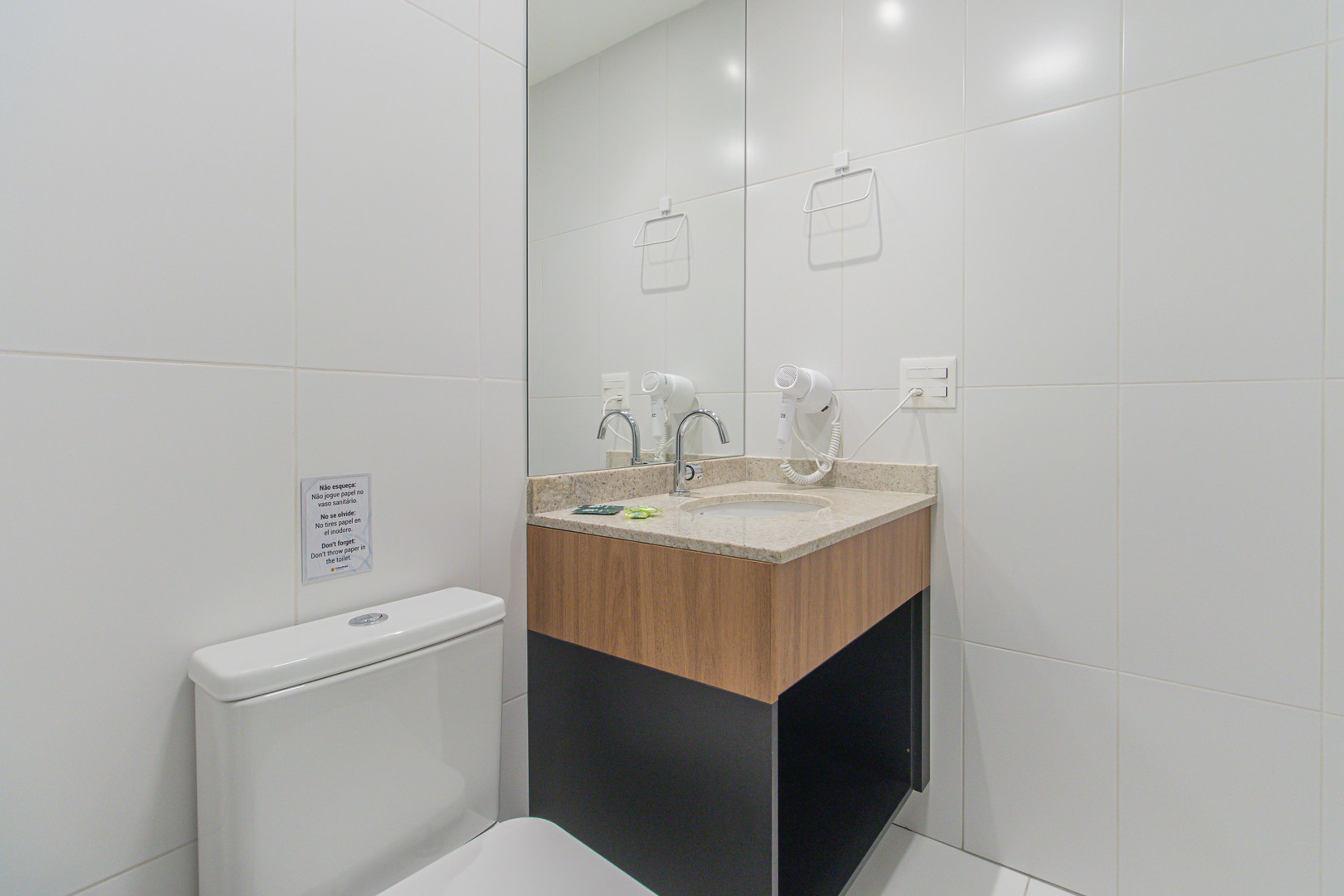 Een moderne badkamer met een wit toilet, een wastafel met een houten blad en een spiegel.