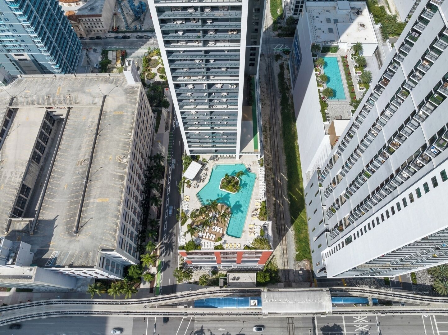 A high-rise building with a rooftop pool, surrounded by other tall buildings.