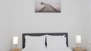 A bedroom with a bed, two bedside tables, and a wall-mounted picture of a pier. - Stylish4BR,5Bds,FREEPARKING,Near New York City, Times Square, WTC,BrooklynBridge (Bayonne)