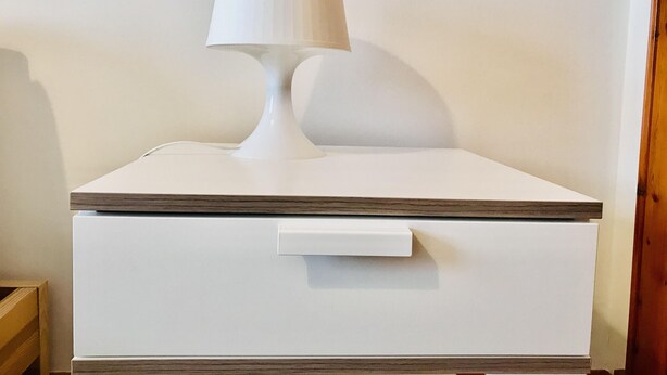 A white bedside table with a lamp and a drawer. - Pipeland Farm Steading (No 4) (St Andrews)