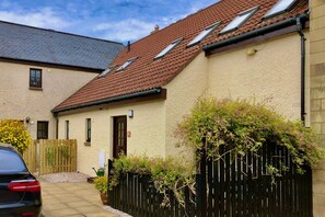A residential building with a sloped roof, multiple windows, and a gated entrance. - Pipeland Farm Steading (No 4) (St Andrews)