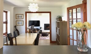 A dining area with a long table, chairs, a television, a fireplace, and a bookshelf. - Pipeland Farm Steading (No 4) (St Andrews)