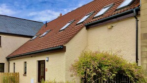 A residential building with a sloped roof, multiple windows, and a small door. - Pipeland Farm Steading (No 4) (St Andrews)