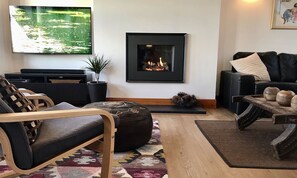 En stue med pejs, fjernsyn og sofa.